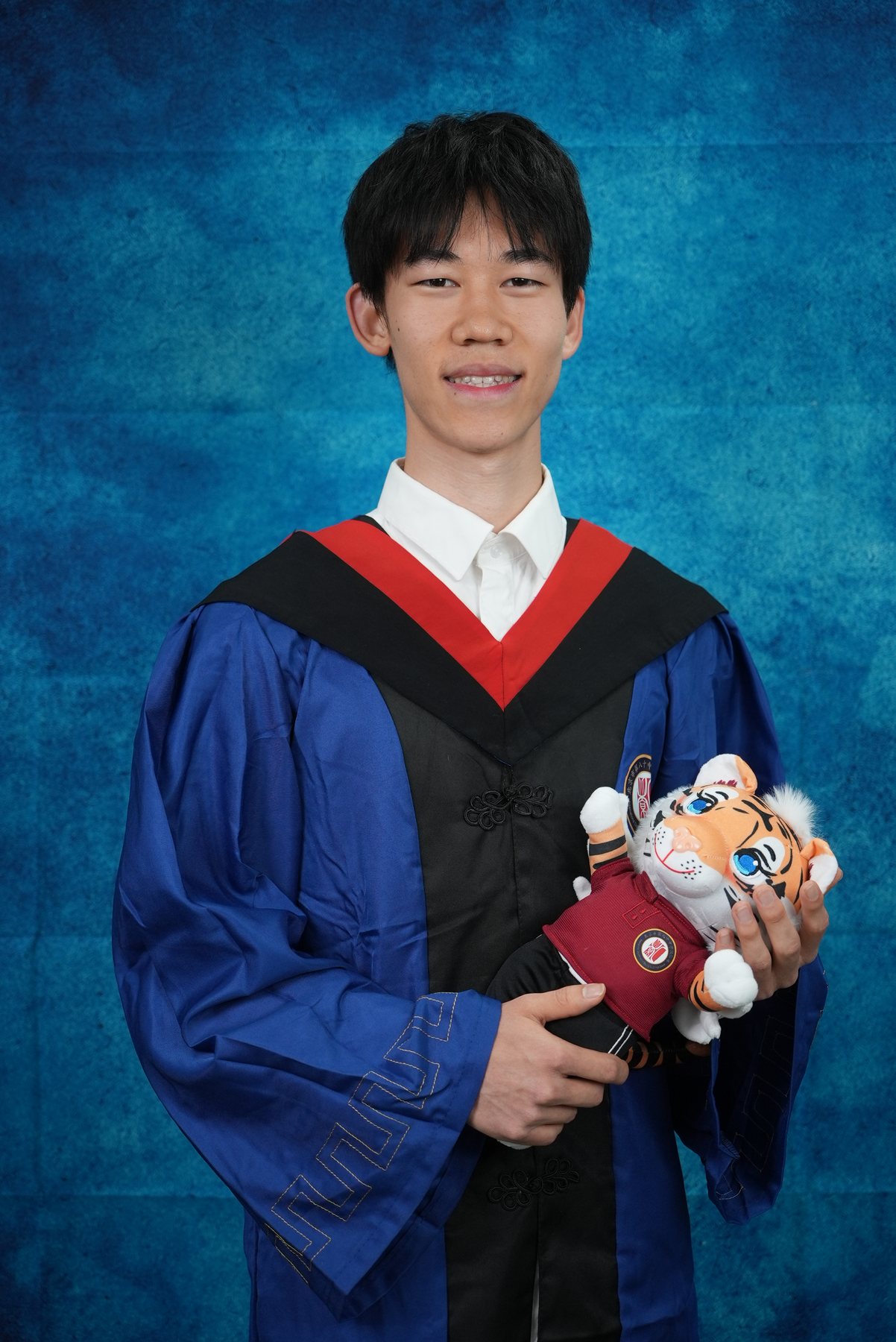 Tenne in graduation attire holding school mascots