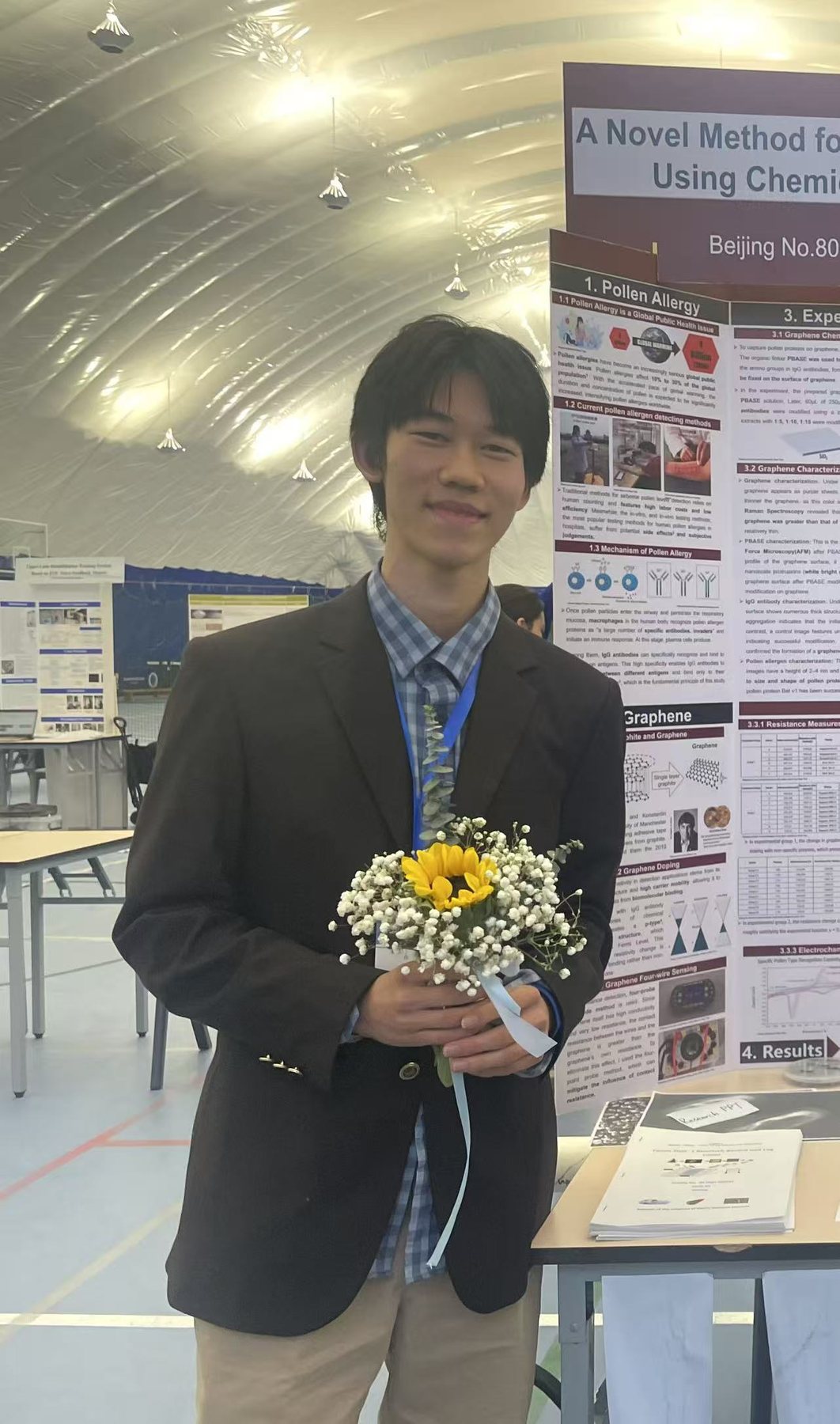 Tenne holding flowers beside a science poster